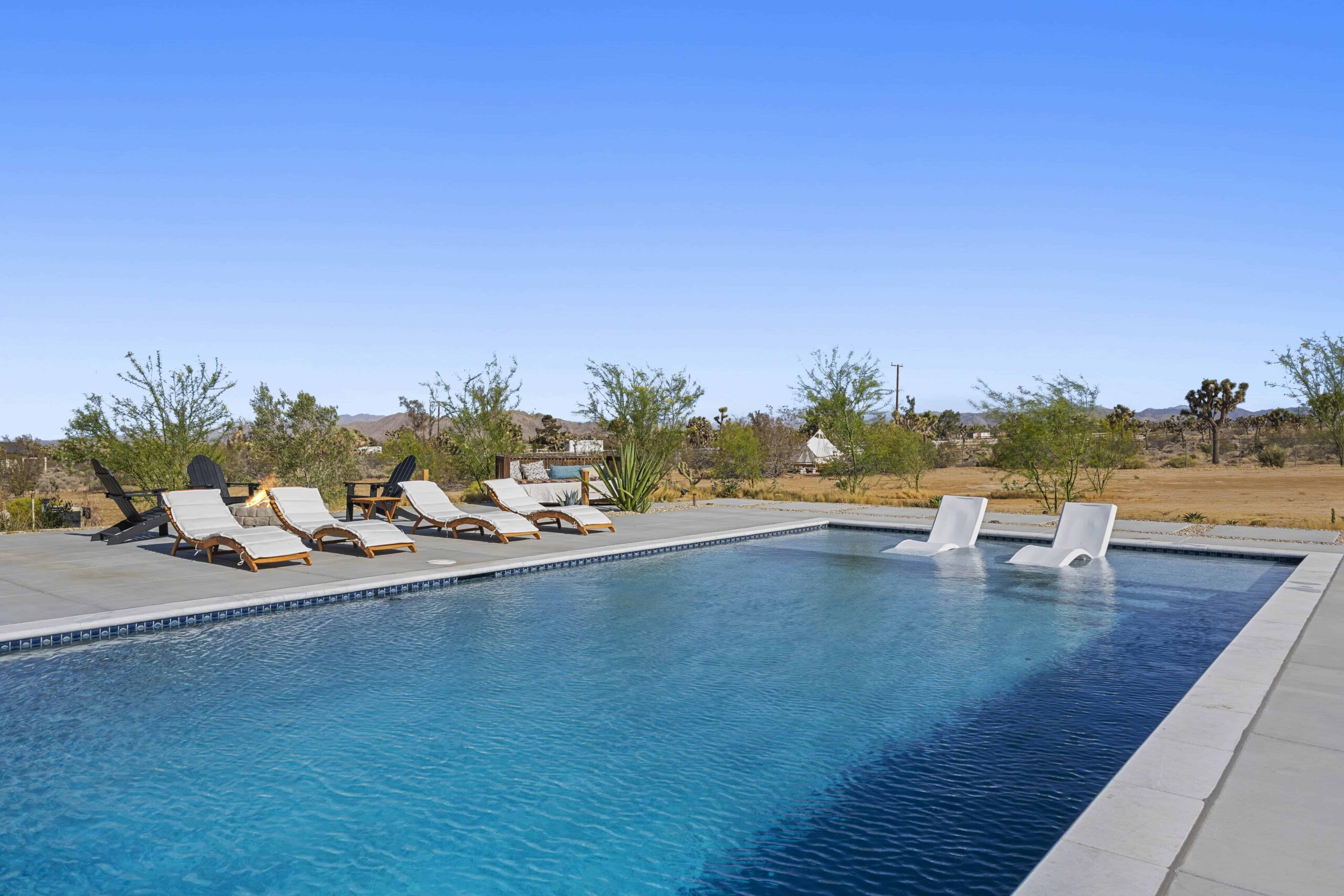 Private swimming pool with poolside lounge chairs at The Desert Shadow